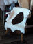 White and brown tibet highland spotted grade a- sheepskin rug draped over white wooden chair by nat’s grade