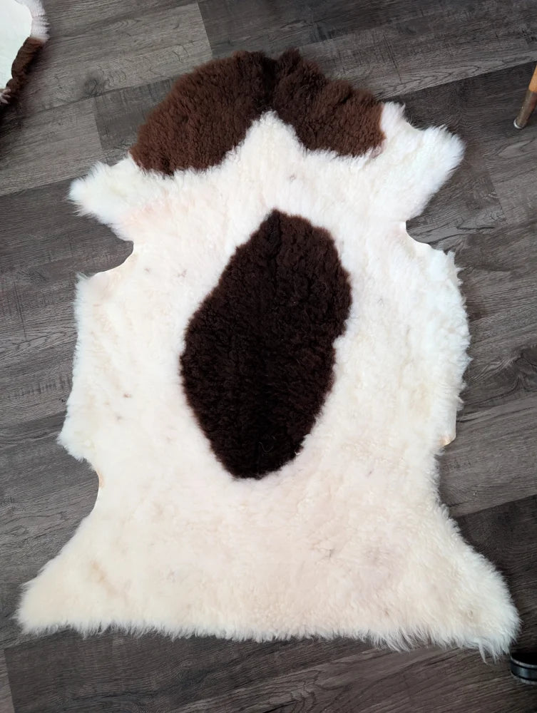 A plush white and brown tibet highland spotted grade a- sheepskin rug with nat’s grade natural fluffy texture