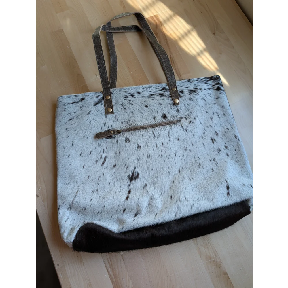 White and black spotted real cowhide tote bag with brown leather handles and zipper closure from cowhide rugs collection