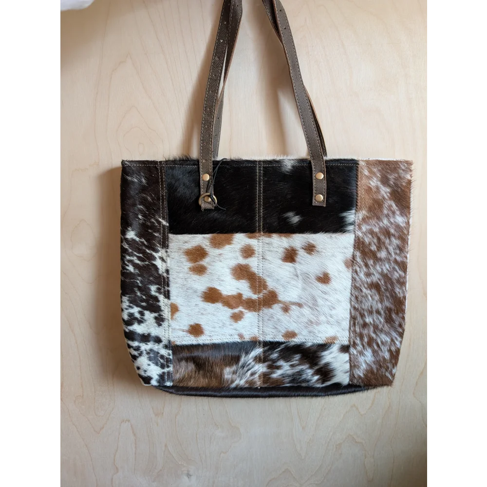 A patchwork real cowhide tote bag with brown and black spots leather straps and metal hardware from the 