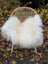 Large long wool natural white icelandic sheepskin draped over a woven wicker chair as a cozy throw