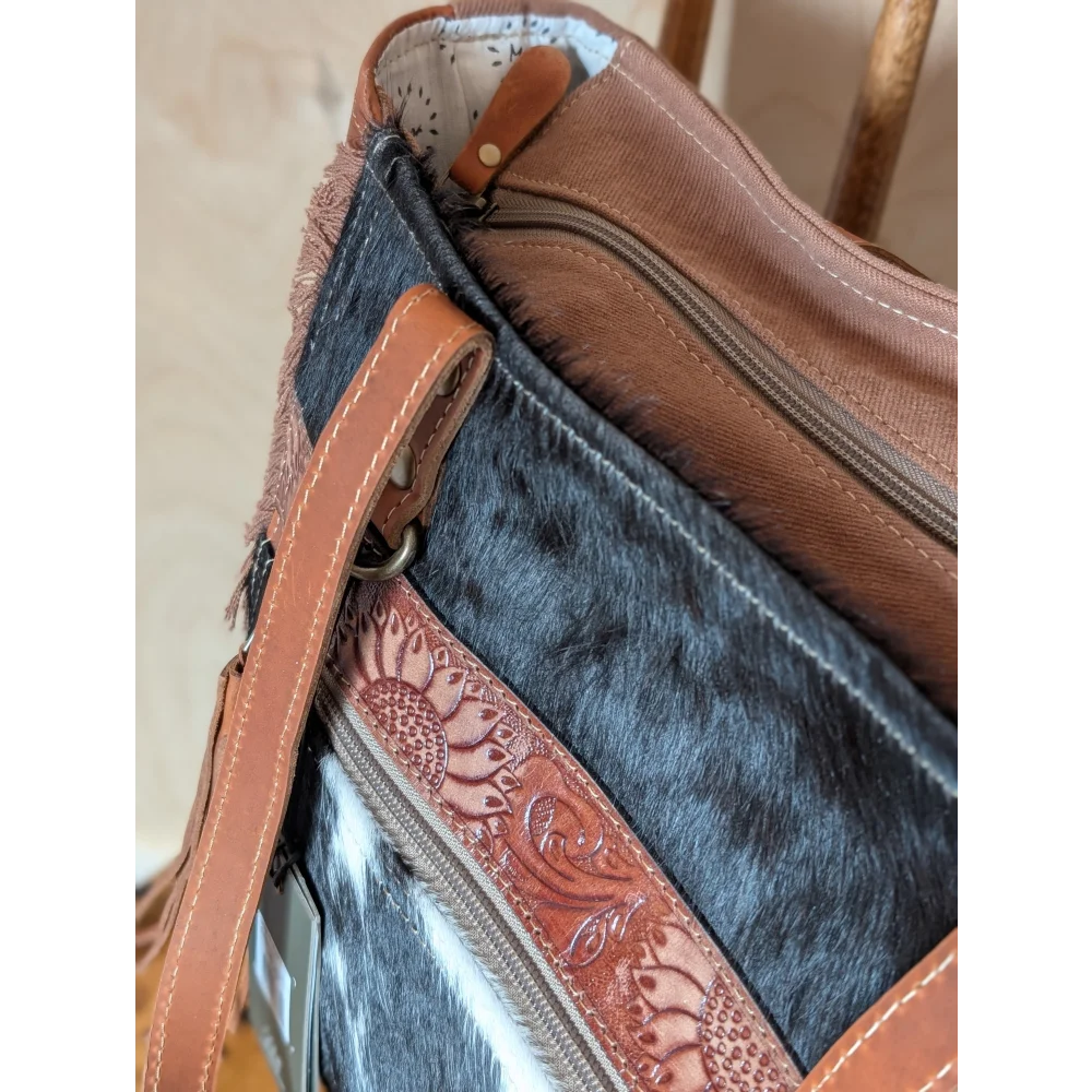 Brown leather strap with sunflower embossing on zipper pull of oakley specks canvas spacious bag with real cowhide lining
