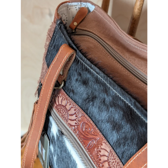 Brown leather strap with sunflower embossing on zipper pull of oakley specks canvas spacious bag with real cowhide lining