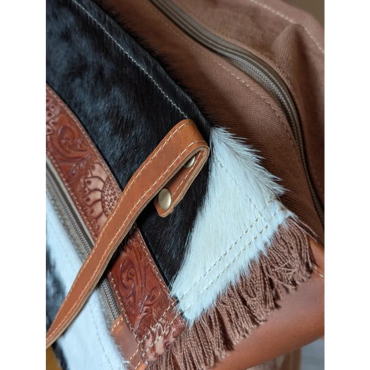 Brown leather strap with embossed floral patterns and brass buckle on oakley bag with real cowhide black and white accents
