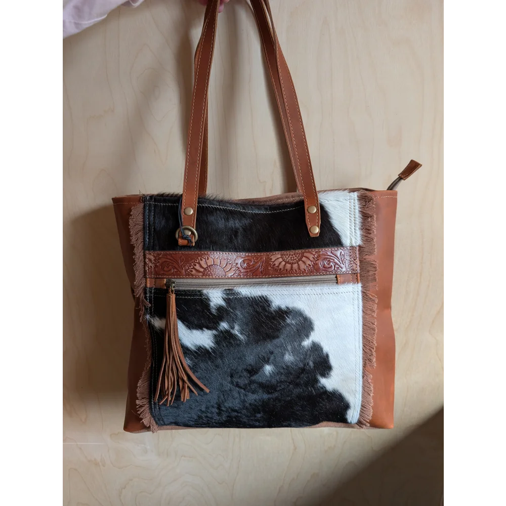 Brown and black real cowhide oakley specks canvas spacious bag with leather straps embossed floral trim and tassel accent