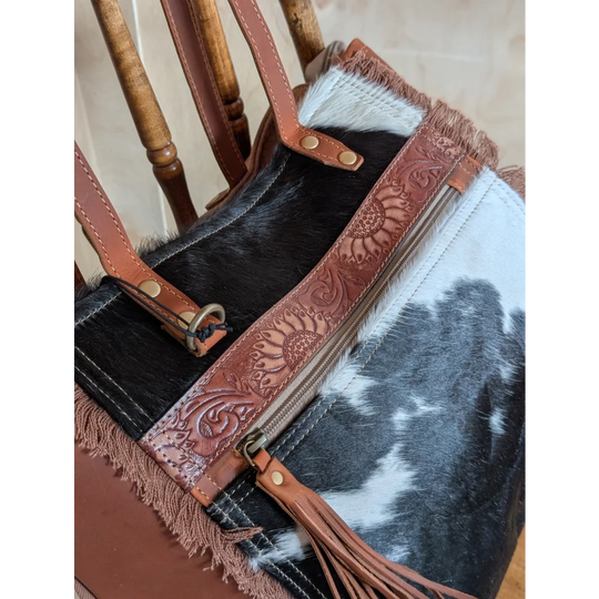 A brown leather oakley bag strap with real cowhide, sunflower embossing, brass hardware, and fringed edges