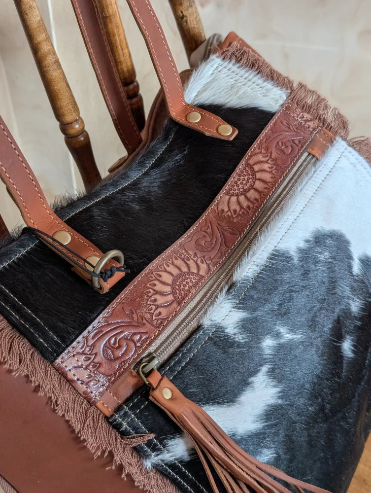 A brown leather oakley bag strap with real cowhide, sunflower embossing, brass hardware, and fringed edges