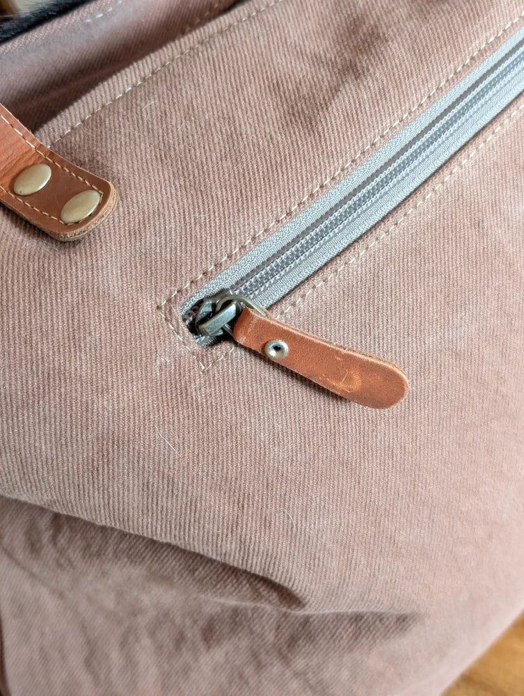 Dusty rose oakley specks canvas bag with spacious design and real cowhide leather zipper pull and strap accents