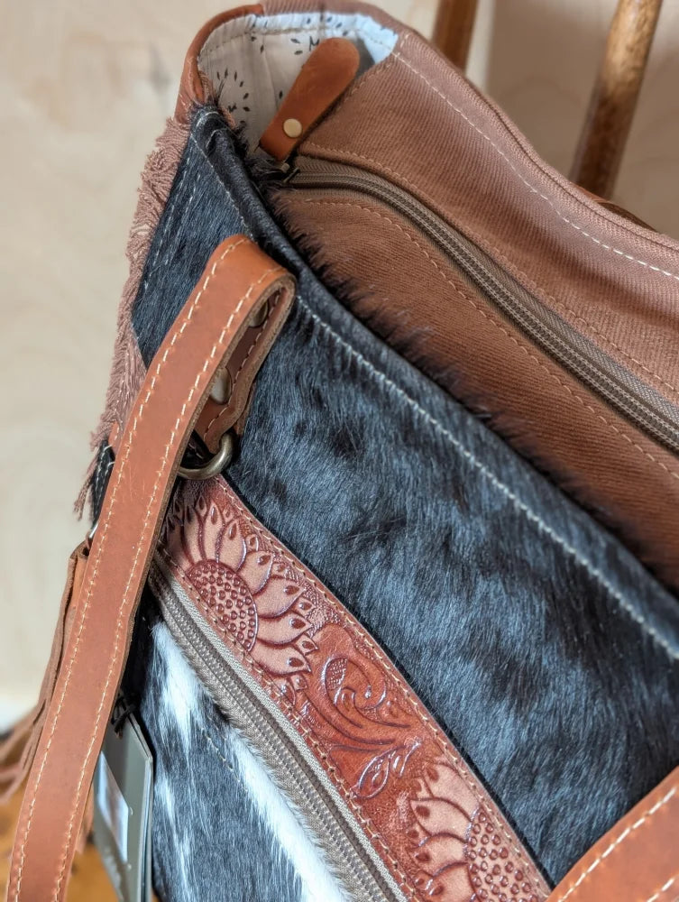 Brown leather strap with sunflower embossing on zipper pull of oakley specks canvas spacious bag with real cowhide lining