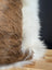Brown and white faux fur cowhide merino sheepskin cushion with plush textured surface for cozy decor