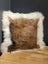 Brown and white cowhide merino sheepskin cushion with plush textured faux fur surface perfect for cozy decor