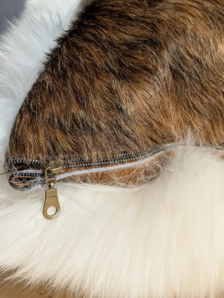 Brown faux fur merino sheepskin cushion with white fluffy trim and metallic zipper in cowhide merino sheepskin style