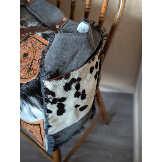 The sunflower weekender bag is a rustic cartwright hand-tooled bag with hair-on hide patchwork and a zippered pocket