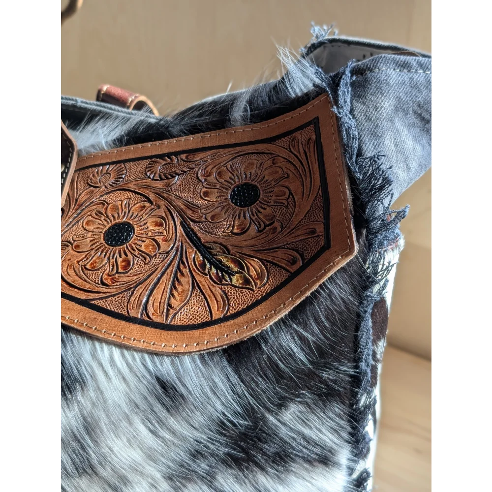 A tan cartwright hand-tooled bag leather strap with floral tooling black stitched detailing and zippered pocket features