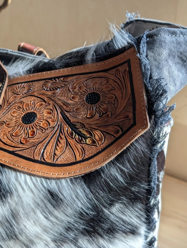 A tan cartwright hand-tooled bag leather strap with floral tooling black stitched detailing and zippered pocket features