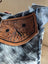 A tan cartwright hand-tooled bag leather strap with floral tooling black stitched detailing and zippered pocket features