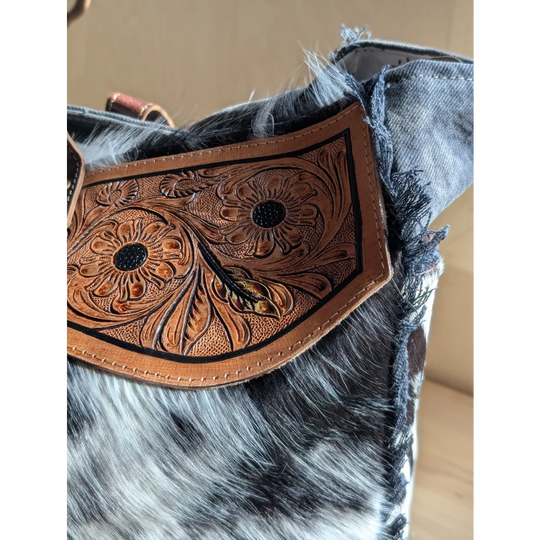 A tan cartwright hand-tooled bag leather strap with floral tooling black stitched detailing and zippered pocket features