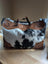The sunflower weekender bag is a black and white hair-on hide duffle with tan leather trim and a zippered pocket