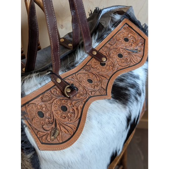 A tan cartwright hand-tooled weekender bag with floral design, dark brown straps, and a zippered pocket detail
