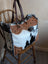 The sunflower weekender bag is a rustic hair-on hide tote with tan cartwright hand-tooled panels and dark brown handles with zippered pocket