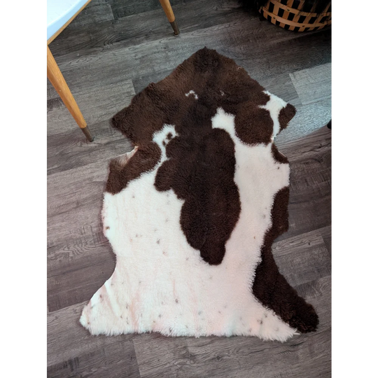 A plush brown and white highland spotted grade a- sheepskin rug with soft fluffy texture perfect for cozy spaces