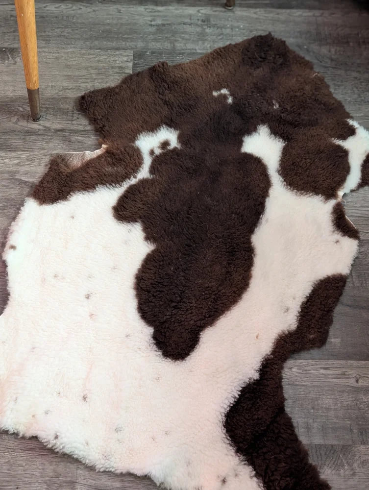 A plush highland spotted grade a- sheepskin rug with natural brown and white spots in an irregular cowhide shape