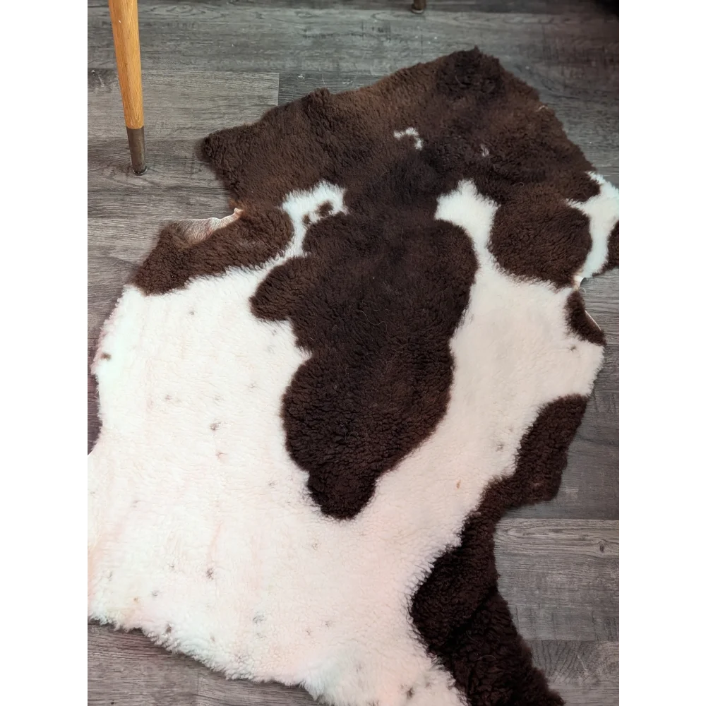 A plush highland spotted grade a- sheepskin rug with natural brown and white spots in an irregular cowhide shape
