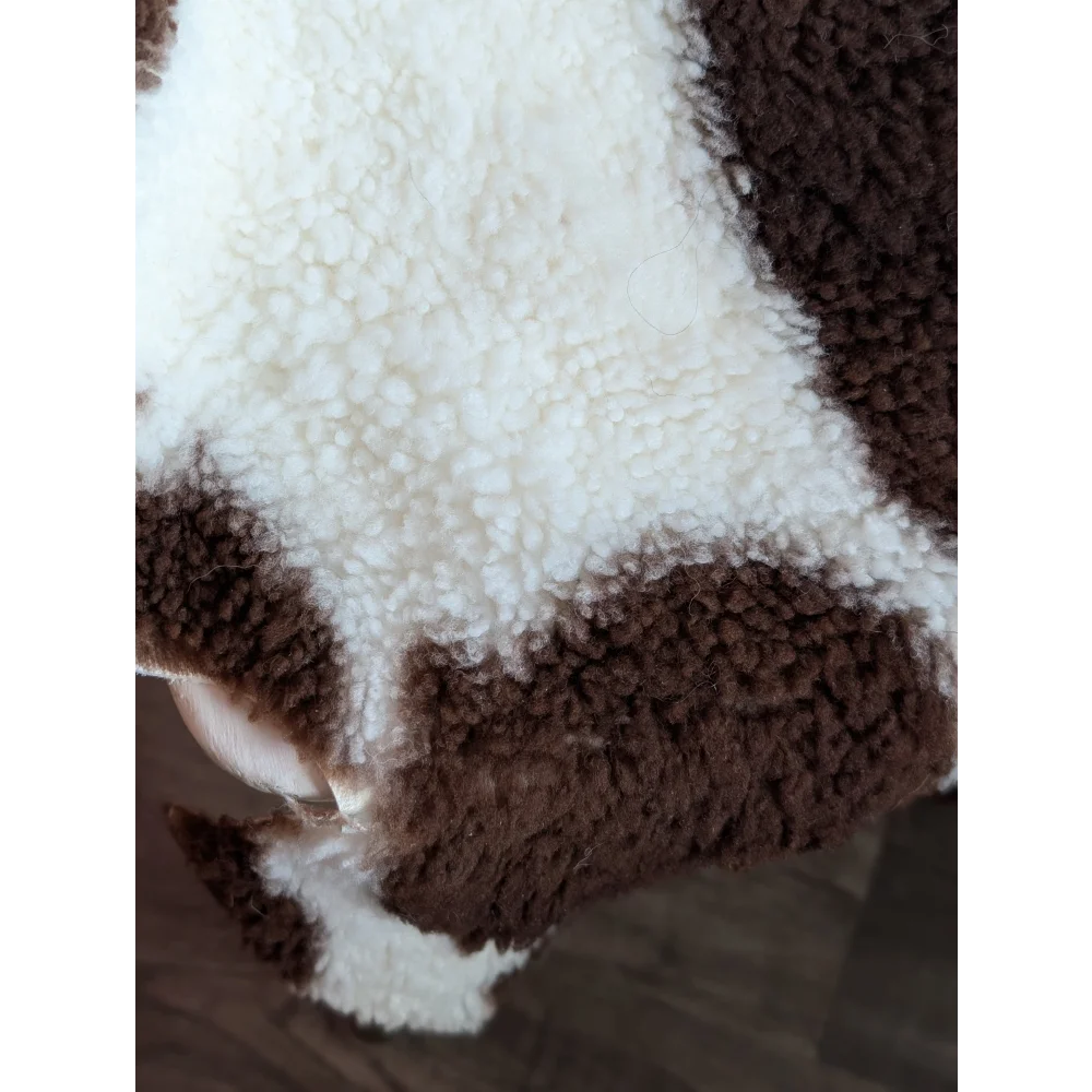 A cozy brown and white cow-print sherpa blanket made from grade a- highland spotted sheepskins with plush texture