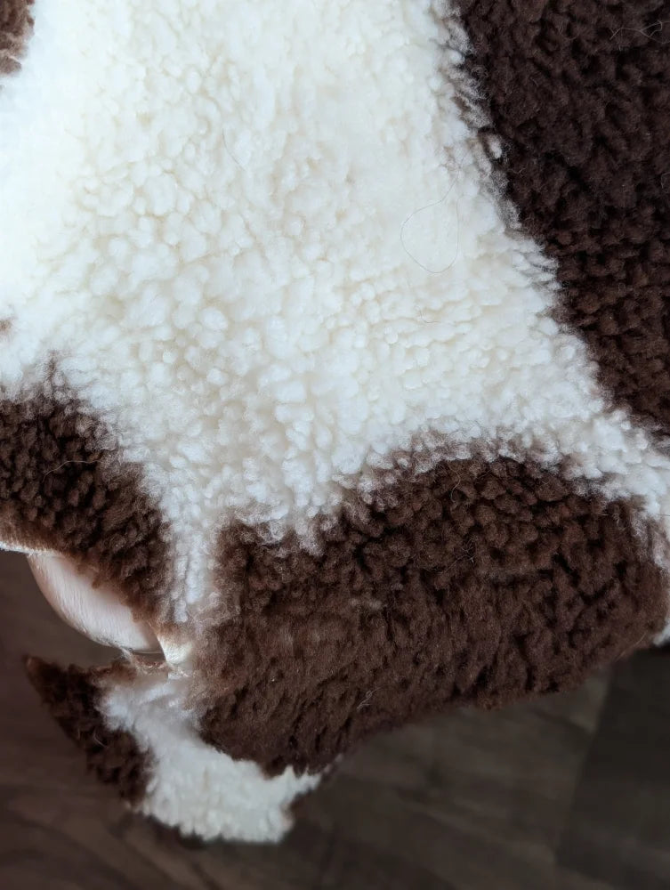 A cozy brown and white cow-print sherpa blanket made from grade a- highland spotted sheepskins with plush texture