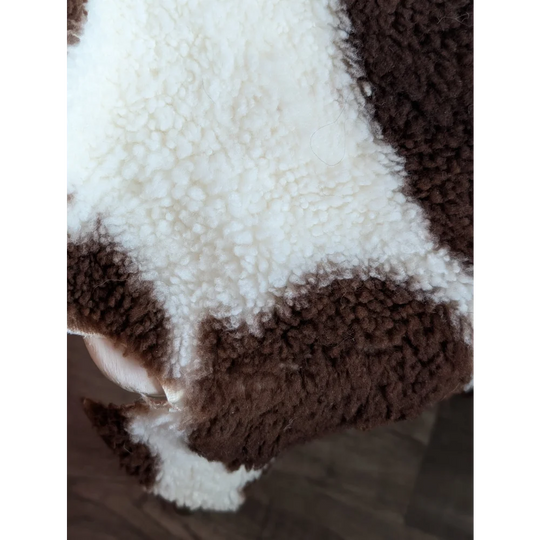 A cozy brown and white cow-print sherpa blanket made from grade a- highland spotted sheepskins with plush texture