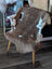 Brown and white tibet highland spotted grade a- sheepskin draped over a vintage wooden chair with light arms
