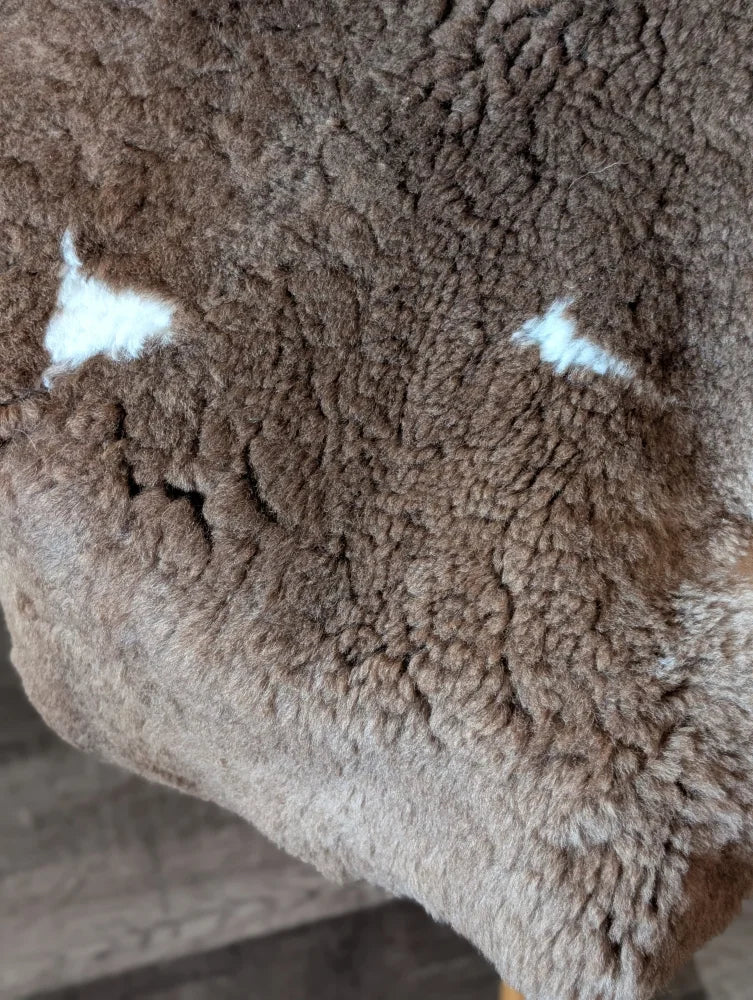 Brown tibet highland spotted grade a- sheepskin blanket with white patches and fluffy textured surface from nat’s grade