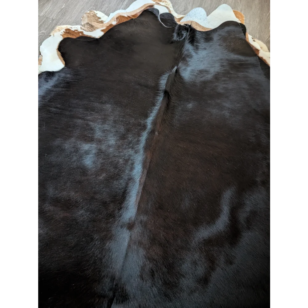 Large cowhide rug 78 x 69 inches with black base and natural irregular border featuring white and tan patches