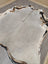 A large lovely cowhide rug measuring 77.5 by 66 inches with gray black and white natural fur patches and irregular edges