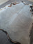 A lovely large cowhide rug in light gray with natural edges and brown and black patches measuring 77.5 x 66 inches