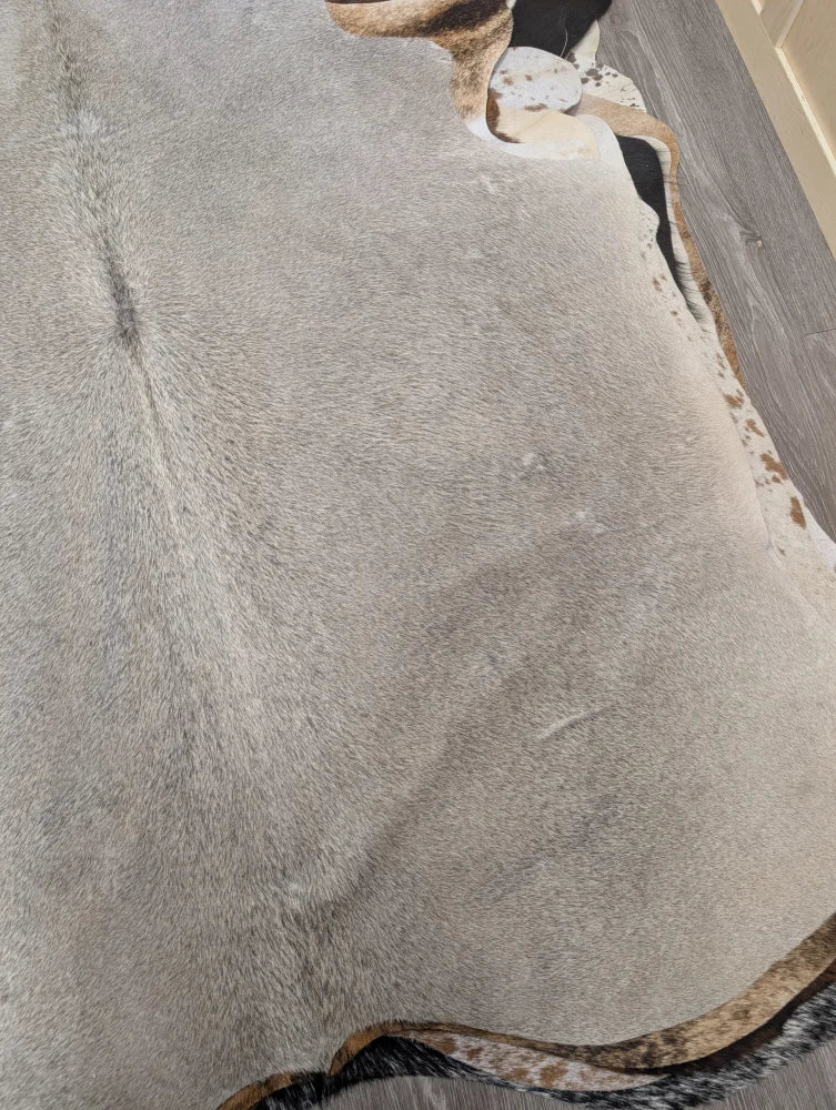 Large gray cowhide rug with natural edges and subtle brown speckles in a lovely cowhide 77.5 by 66 inches