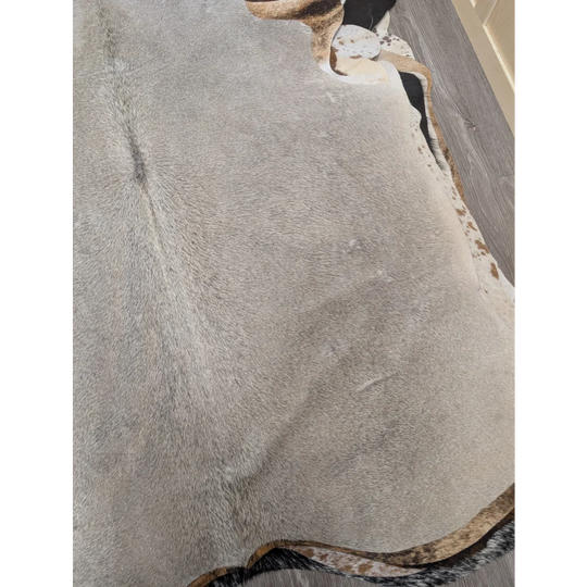 Large gray cowhide rug with natural edges and subtle brown speckles in a lovely cowhide 77.5 by 66 inches