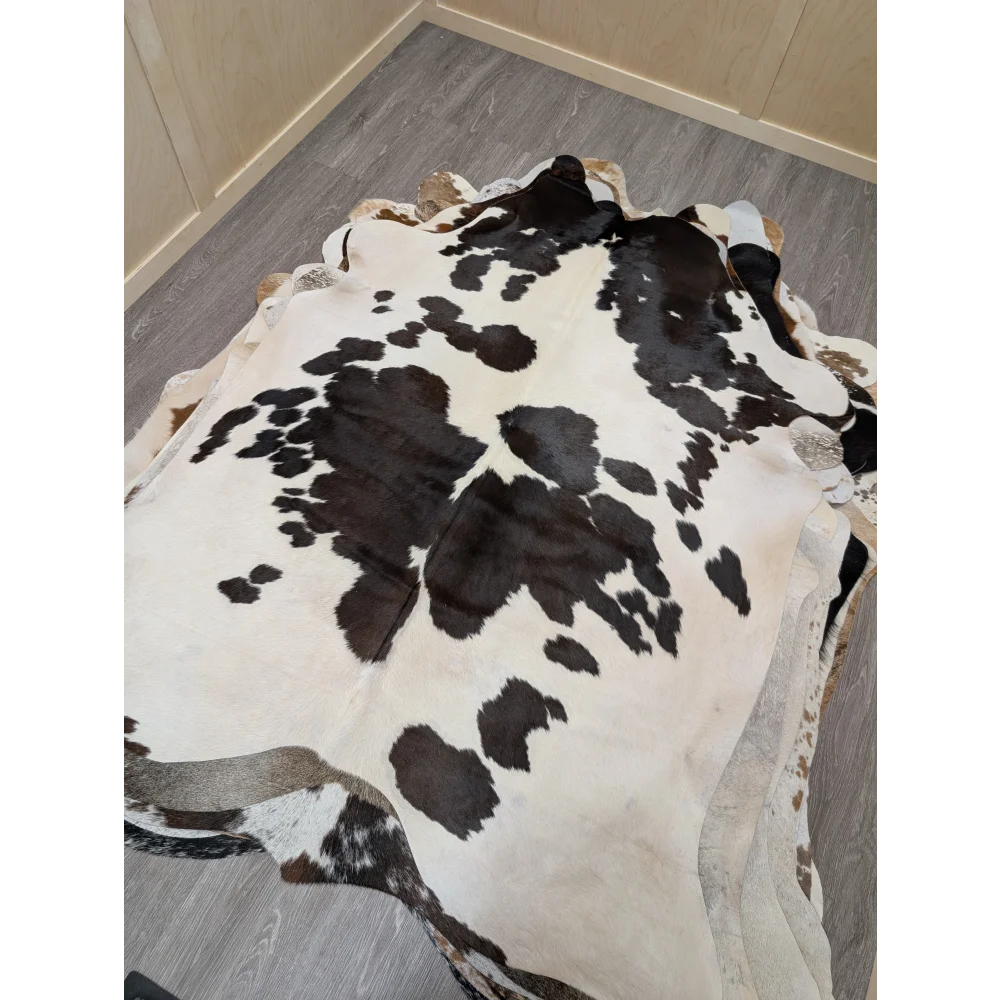 Large lovely cowhide rug with a black and white spotted pattern and irregular edges measuring 77 x 64 inches