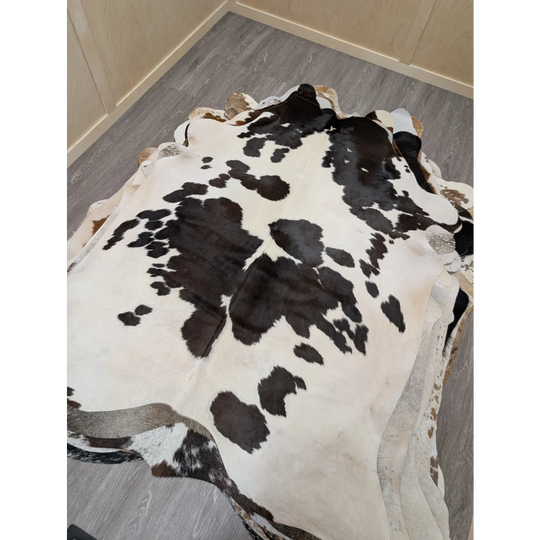 Large lovely cowhide rug with a black and white spotted pattern and irregular edges measuring 77 x 64 inches