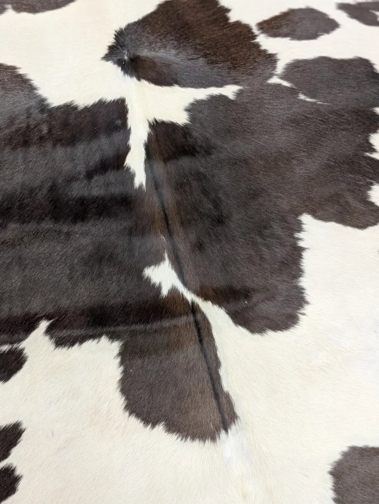 A lovely black and white large cowhide rug with natural textured surface measuring 77 by 64 inches