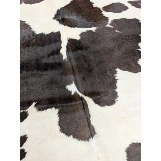 A lovely black and white large cowhide rug with natural textured surface measuring 77 by 64 inches