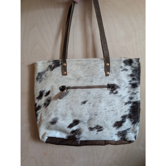White and black real cowhide tote bag with brown leather straps and trim perfect for cowhide rug lovers