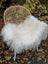 A plush natural white icelandic sheepskin throw with long wool draped over a wicker chair for cozy decor