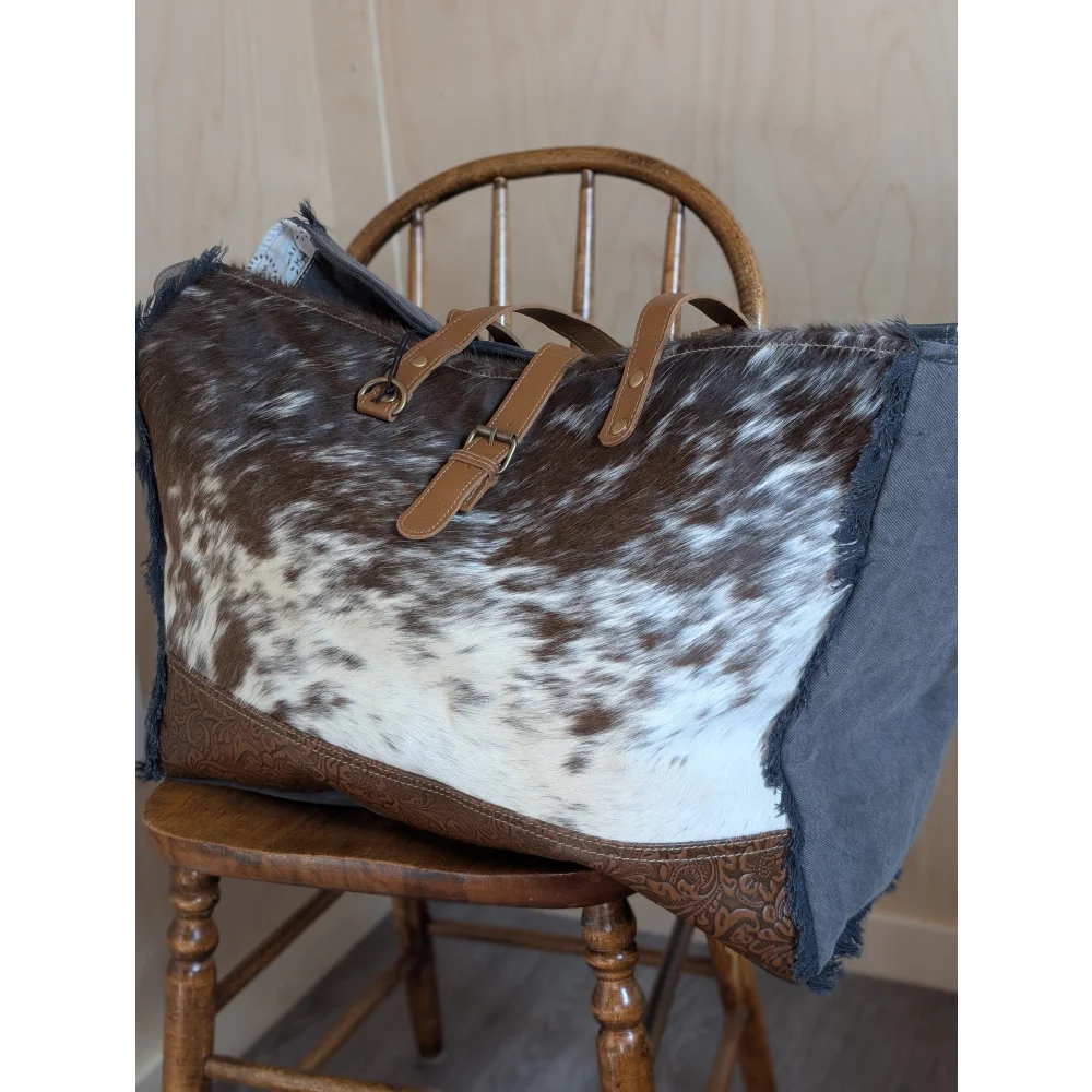 Brown and white cowhide duffle bag with tan leather straps and embossed panel from angus oliver matty affair canvas collection