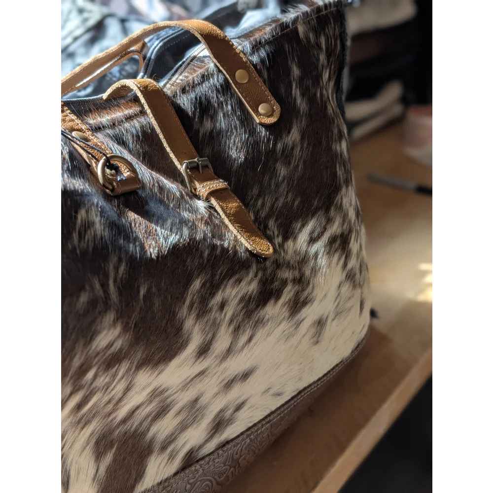 Brown and white cowhide matty affair canvas weekender tote bag with tan leather straps and hardware by angus oliver