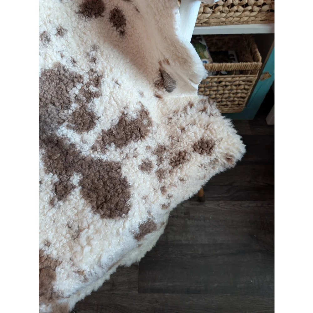 Cream-colored highland spotted sheepskin blanket with brown fluffy patches grade a- sheepskins for cozy use