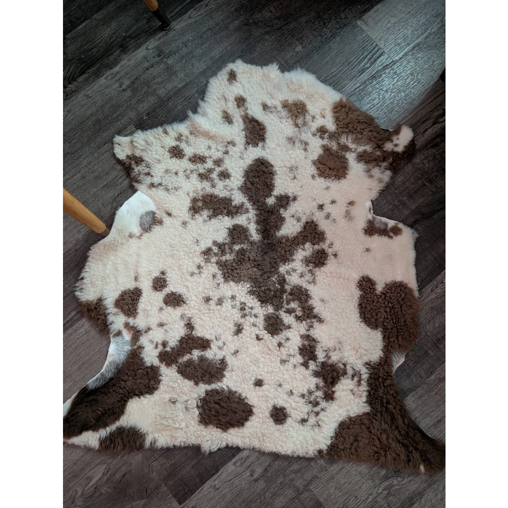 A plush cream and brown highland spotted grade a- sheepskin rug with a soft fluffy texture
