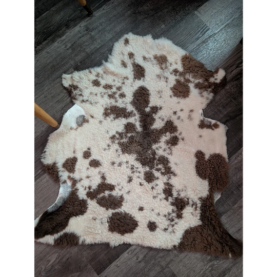 A plush cream and brown highland spotted grade a- sheepskin rug with a soft fluffy texture