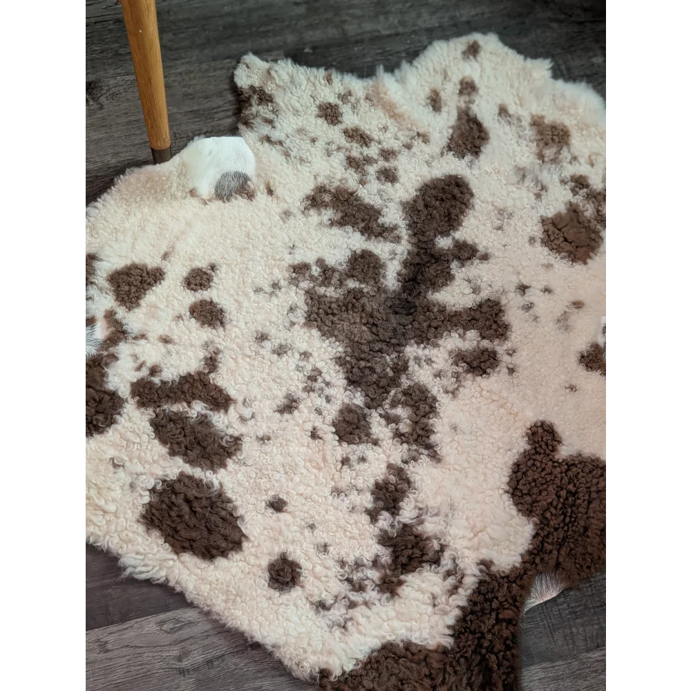 A plush cream and brown highland spotted sheepskin rug with soft fluffy texture grade a sheepskins