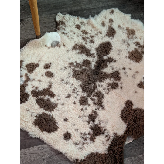 A plush cream and brown highland spotted sheepskin rug with soft fluffy texture grade a sheepskins